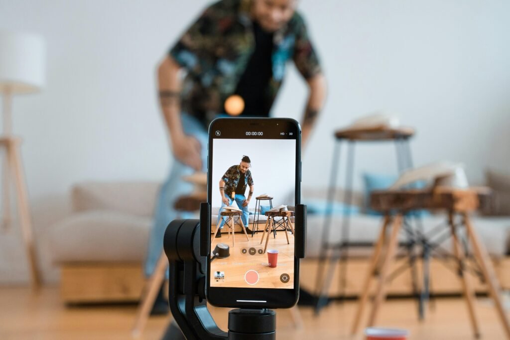 Man recording video content with smartphone on a tripod in a cozy living room.
